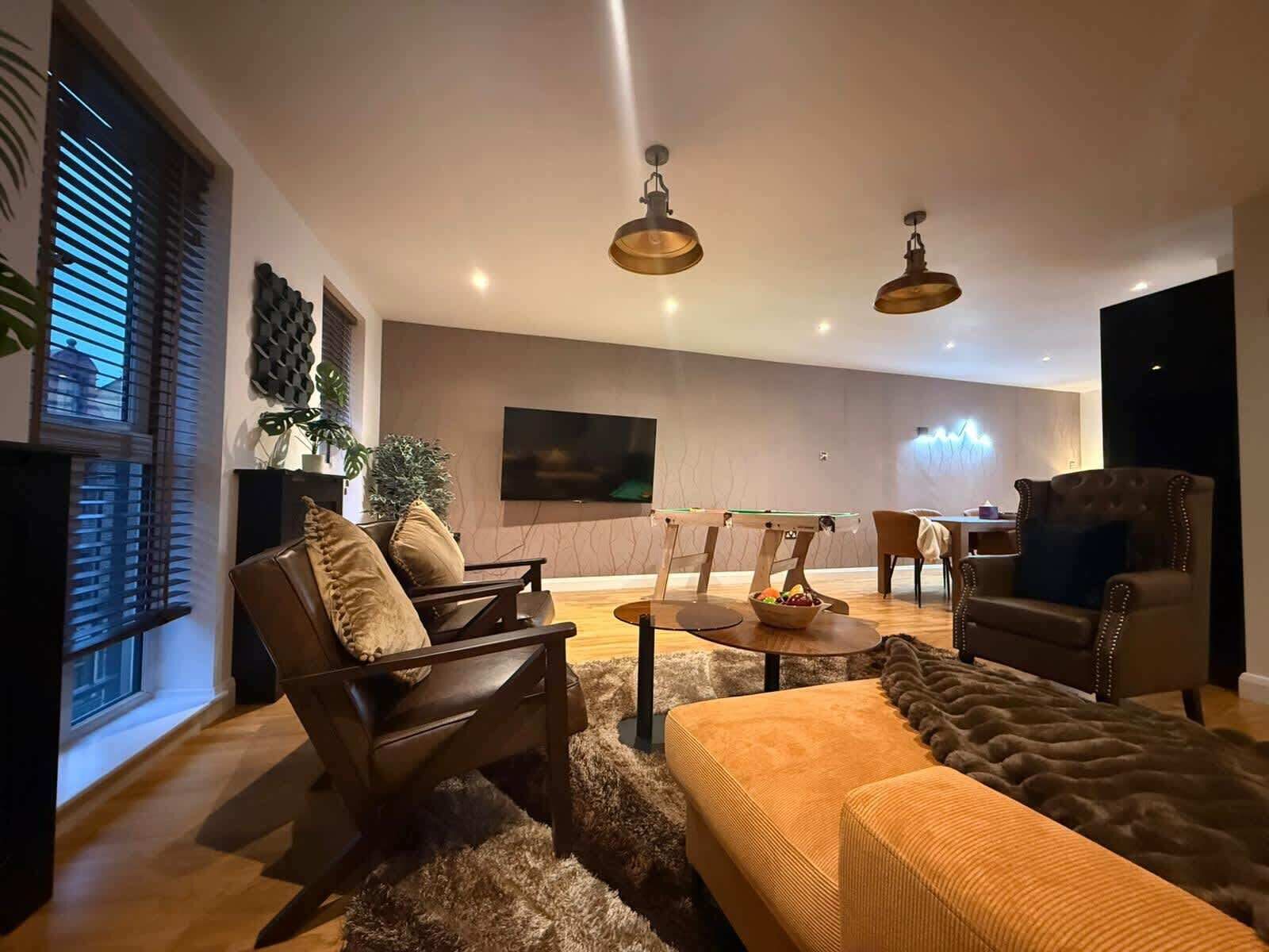 A modern living room with a pool table, comfortable seating, and a flat-screen TV.