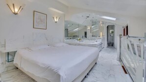 Camera da letto moderna con un letto grande, cabina armadio e bagno con specchio ampio e mobile toilette.