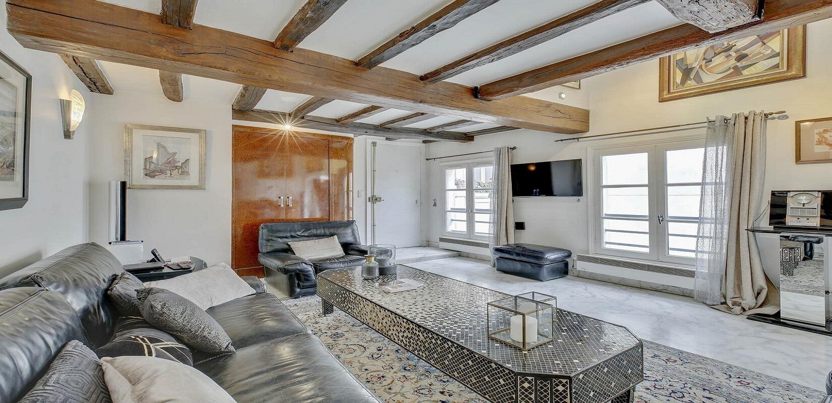 Ein geräumiges Wohnzimmer mit einer Ledersofa, einem Couchtisch und einem an der Wand befestigten Fernseher.