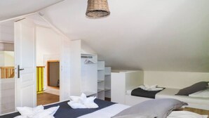 Une chambre avec deux lits, un luminaire suspendu et une armoire.