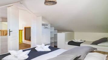 A bedroom with two beds, a hanging light fixture, and a wardrobe.