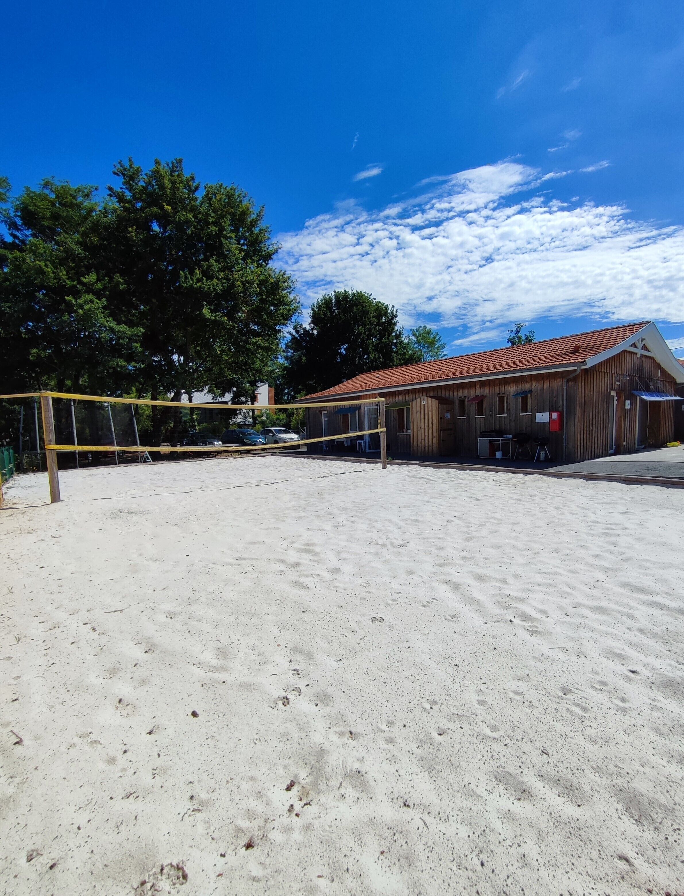 Un terrain de volleyball de plage, avec un bâtiment en bois en arrière-plan.