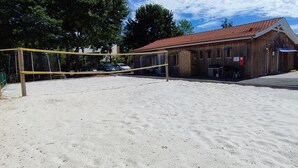 Un terrain de volleyball de plage, avec un bâtiment en bois en arrière-plan.
