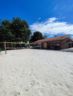 Ein Sandvolleyballfeld mit einem Holzgebäude im Hintergrund.