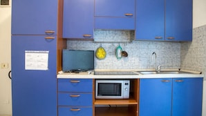 A compact kitchen with blue cabinets, a microwave, a sink, and a small countertop. - Comfy Accommodation With Balcony (Eraclea)
