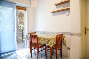 A dining area with a table and four chairs, a sliding glass door leading to an outdoor area, and a tiled floor. - Comfy Accommodation With Balcony (Eraclea)