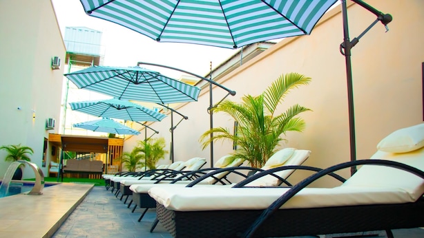 Un espace aménagé au bord de la piscine, avec des chaises longues et des parasols à rayures.