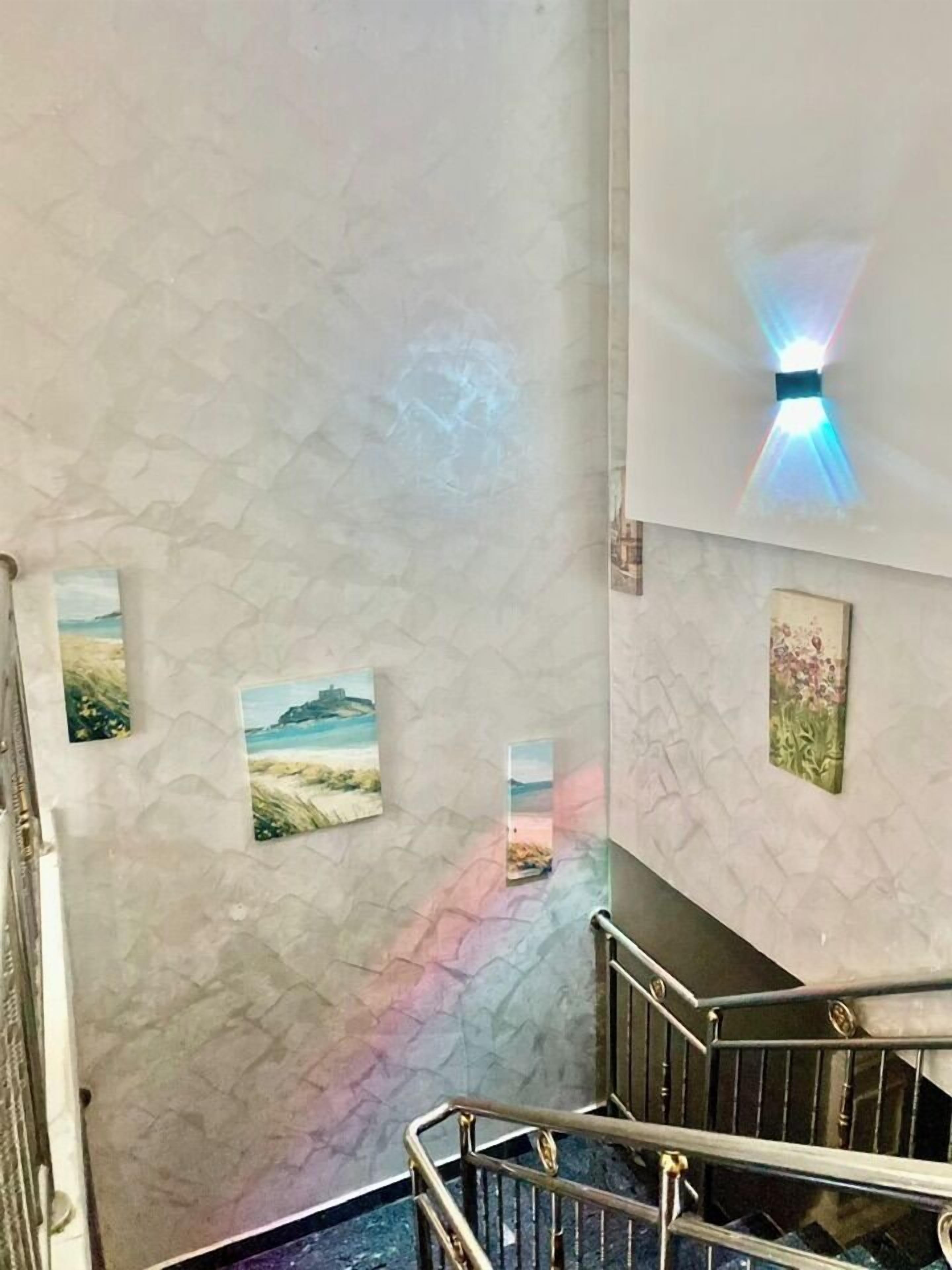 Una escalera con pared de mármol y cuadros enmarcados.