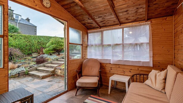 Eine Holzblockhütte mit gemütlicher Einrichtung, inklusive Holzboden, einem Sessel, einem kleinen Tisch und einer Couch.