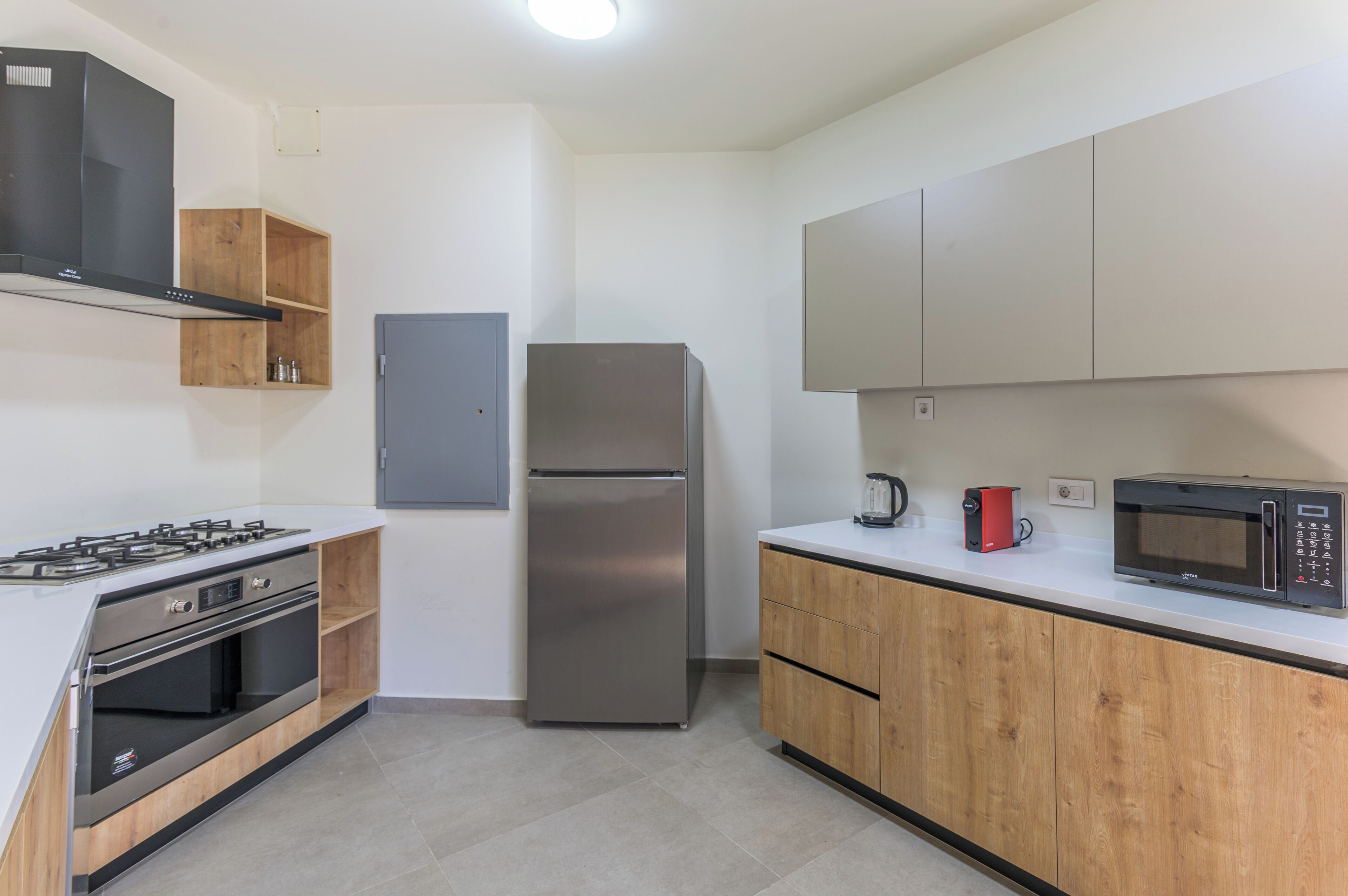 A modern kitchen with a stainless steel refrigerator, built-in oven, and microwave.