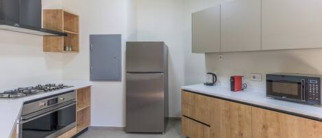 A modern kitchen with a stainless steel refrigerator, built-in oven, and microwave.