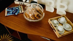 A wooden table with a glass-covered food display, tea packets, and a tea box labeled "TEA". - Palazzo Armony (Bitritto)