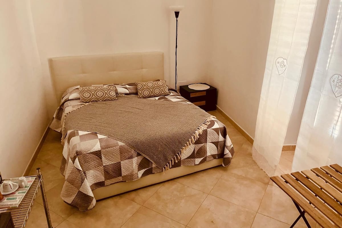 Una camera da letto con un letto, un comodino, una lampada e una sedia.