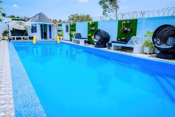 A swimming pool with lounge chairs and a small building with a sloped roof.