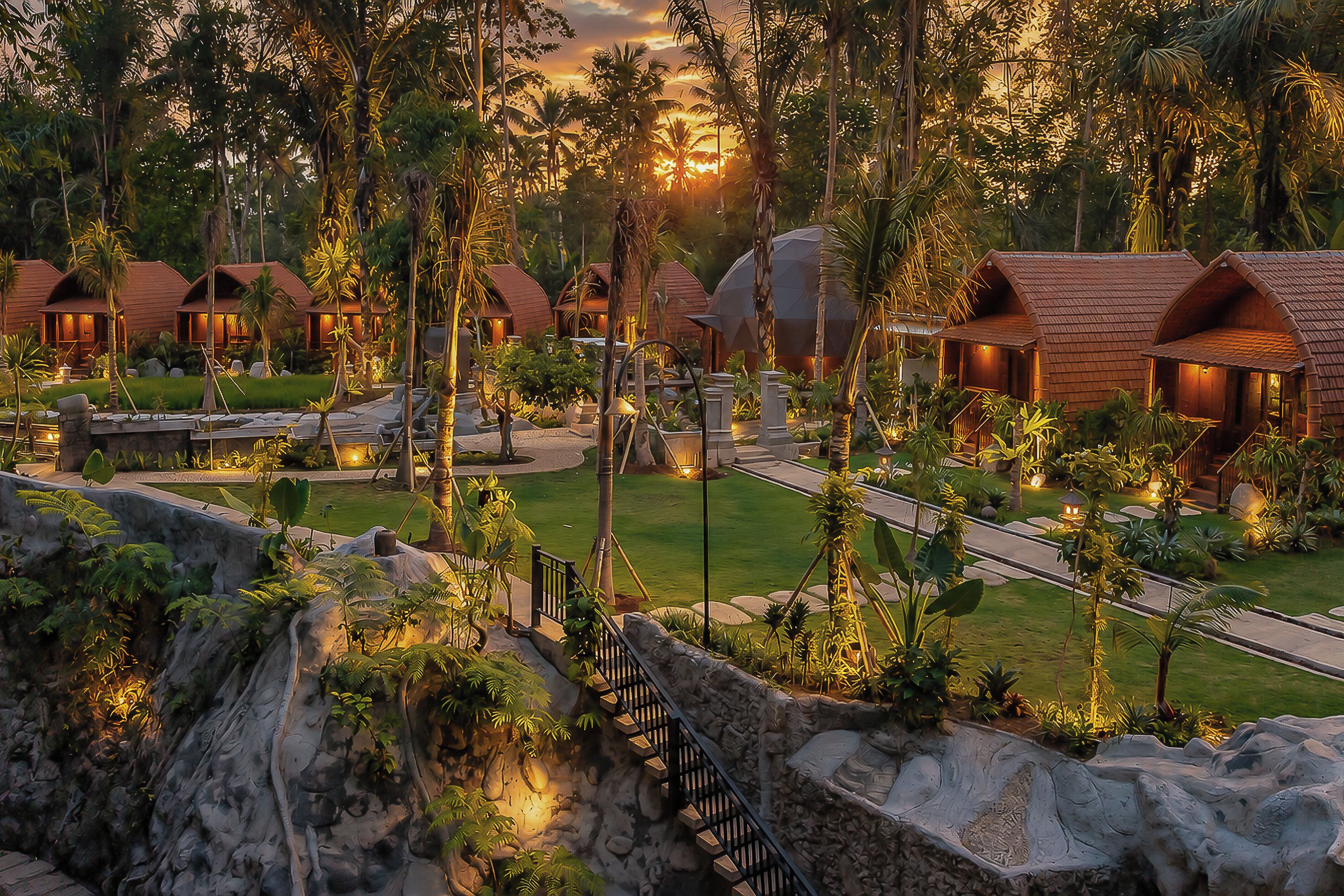 Un resort con varias cabañas, un camino central y un jardín ajardinado.