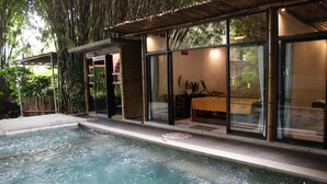 A spa area with a hot tub, glass doors, and a table with chairs. - The Jungle Pots (Payangan)