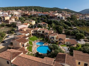 A residential area with a swimming pool surrounded by houses with terracotta roofs. - Cozy Accommodation in Beautiful Sardinia (Badesi)