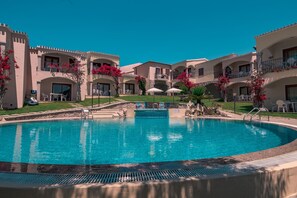 A swimming pool surrounded by a courtyard with multiple buildings, each with balconies and outdoor seating. - Cozy Accommodation in Beautiful Sardinia (Badesi)