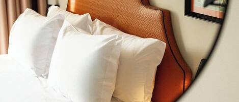 A bed with a headboard, pillows, and a wall with framed artwork.