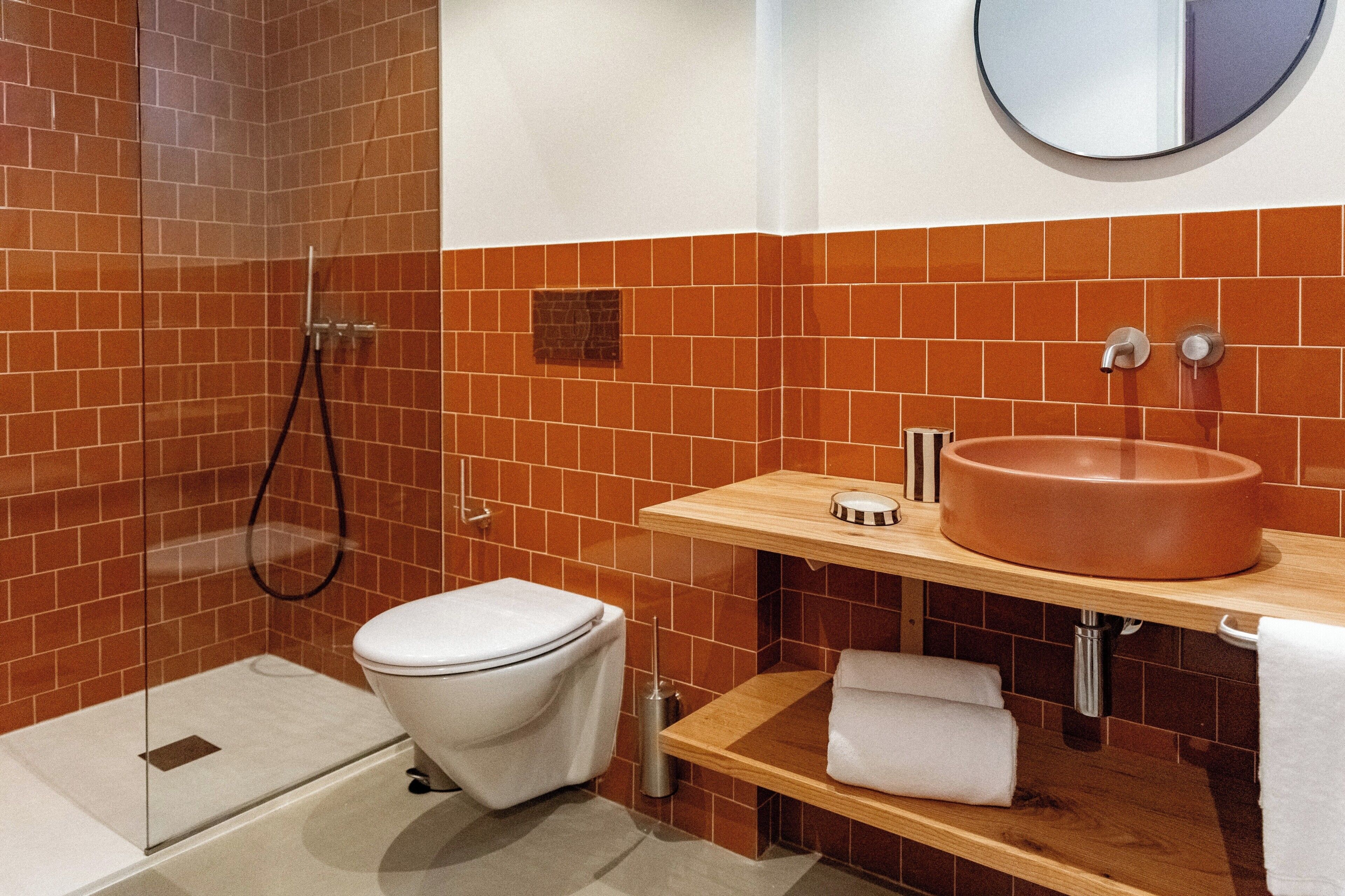 A bathroom with a shower, toilet, sink, and mirror.