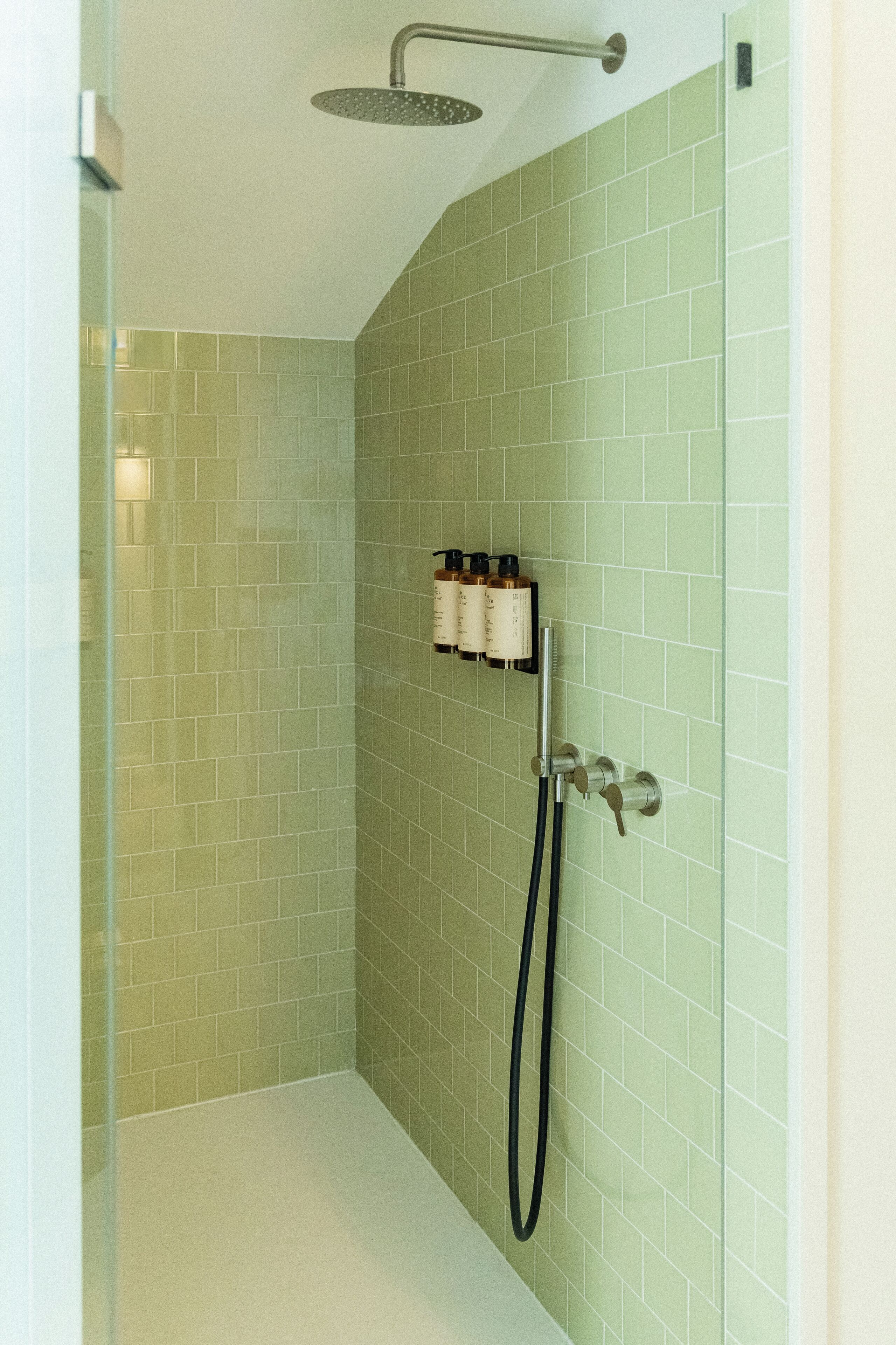 A shower with a handheld showerhead, a handheld shower nozzle, and a wall-mounted faucet.