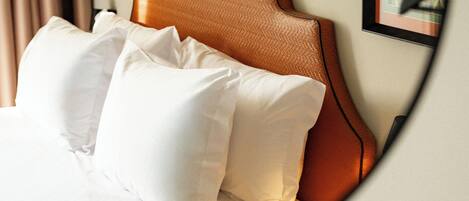 Una cama con cabecera, almohadas y un cuadro colgado en la pared.