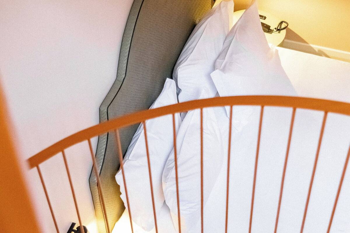 A staircase leading to a bed with a headboard, a bedside lamp, and a wall-mounted clock.