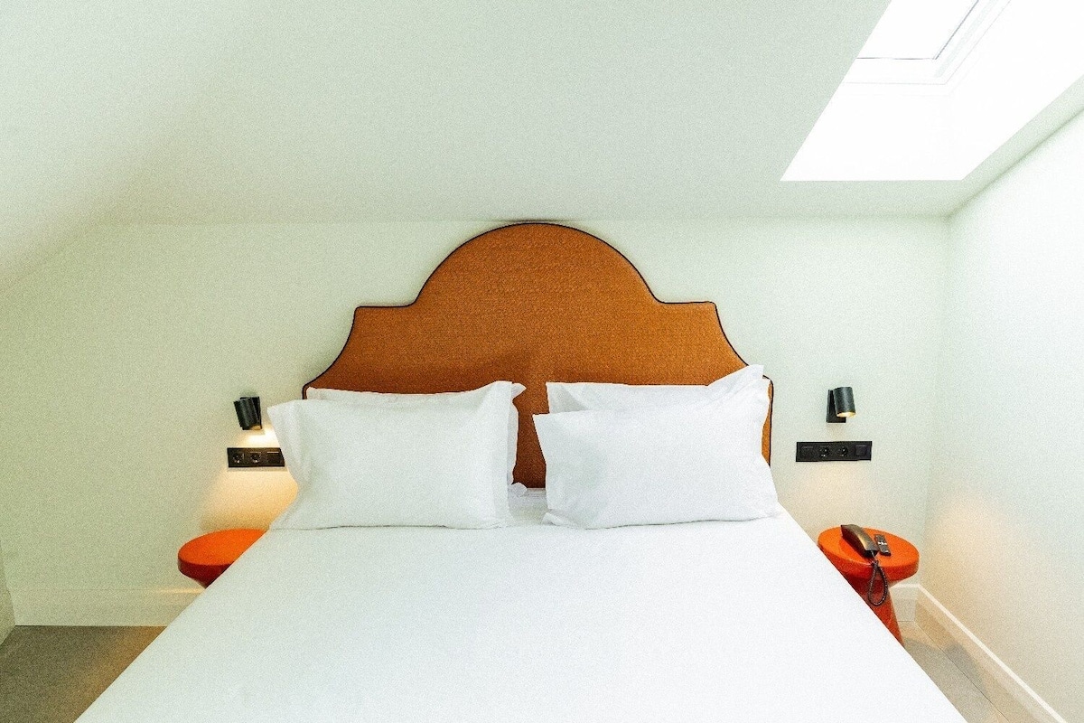 A bed with a wooden headboard, two white pillows, and two bedside tables with lamps.