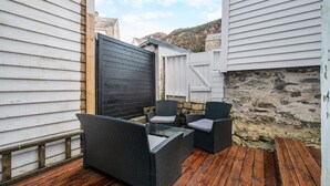 An outdoor patio area with wicker furniture and a wooden deck. - The Heart of Bergen - Central & Stylish (Bergen)