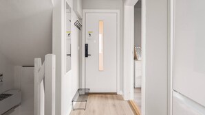 A narrow hallway with white walls, a wooden floor, and a door at the end. - The Heart of Bergen - Central & Stylish (Bergen)
