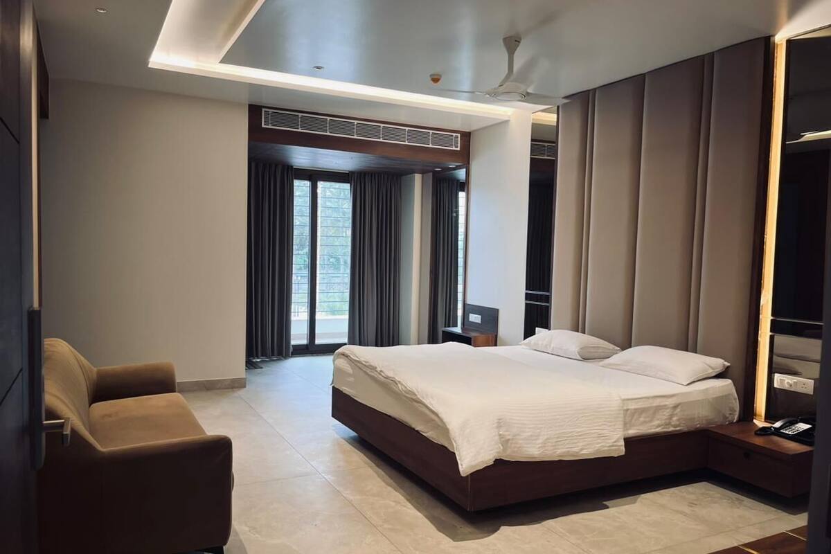 Quarto de hotel moderno com uma cama grande, um sofá e uma escrivaninha com telefone.