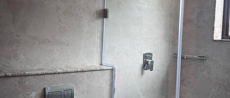 Et badeværelse med toilet, bruseniche og en balje.
