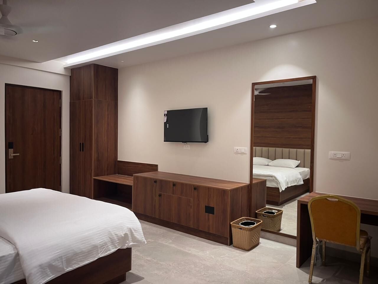 Een moderne hotelkamer met een bed, een bureau, een televisie en een grote spiegel.