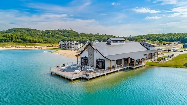Ein Hotel am Wasserufer mit einem großen Gebäude, einer Anlegestelle und einem Strand im Hintergrund.
