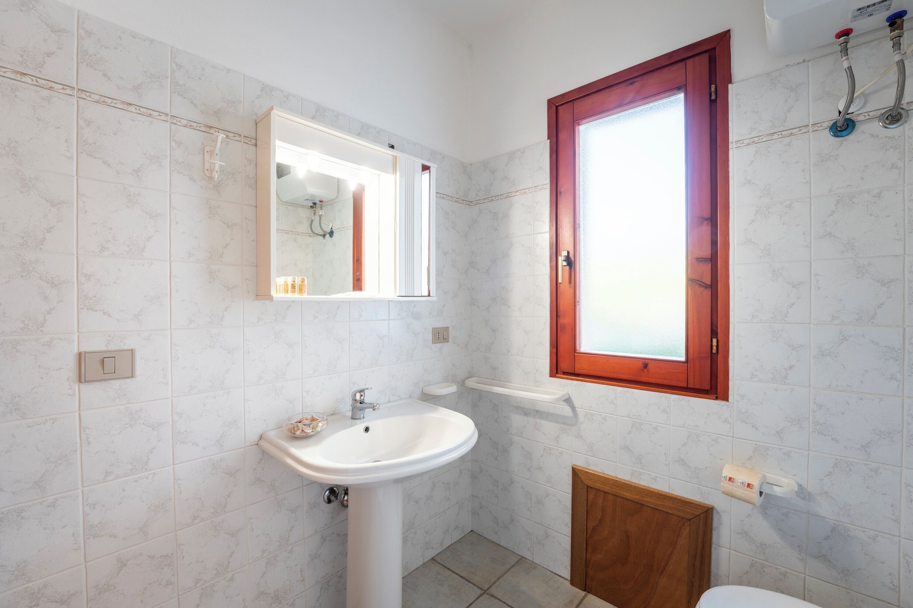 Un bagno con lavandino, specchio e water bianchi.