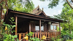 A rustic wooden cabin with a porch, surrounded by lush greenery. - Dulang Resort & Resto (Lembang)