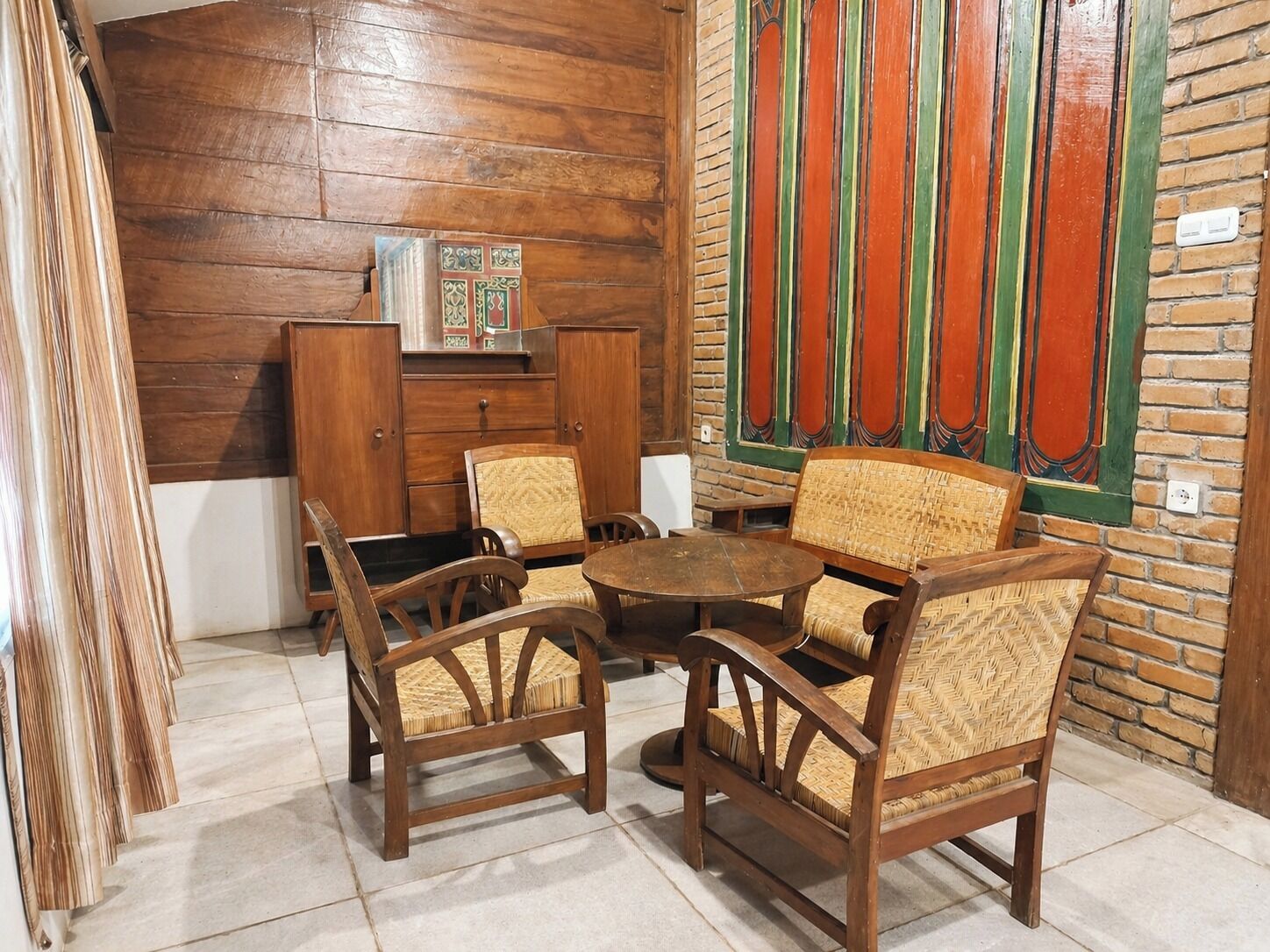 A room with wooden furniture, including a table and chairs, a cabinet, and a decorative wall panel.