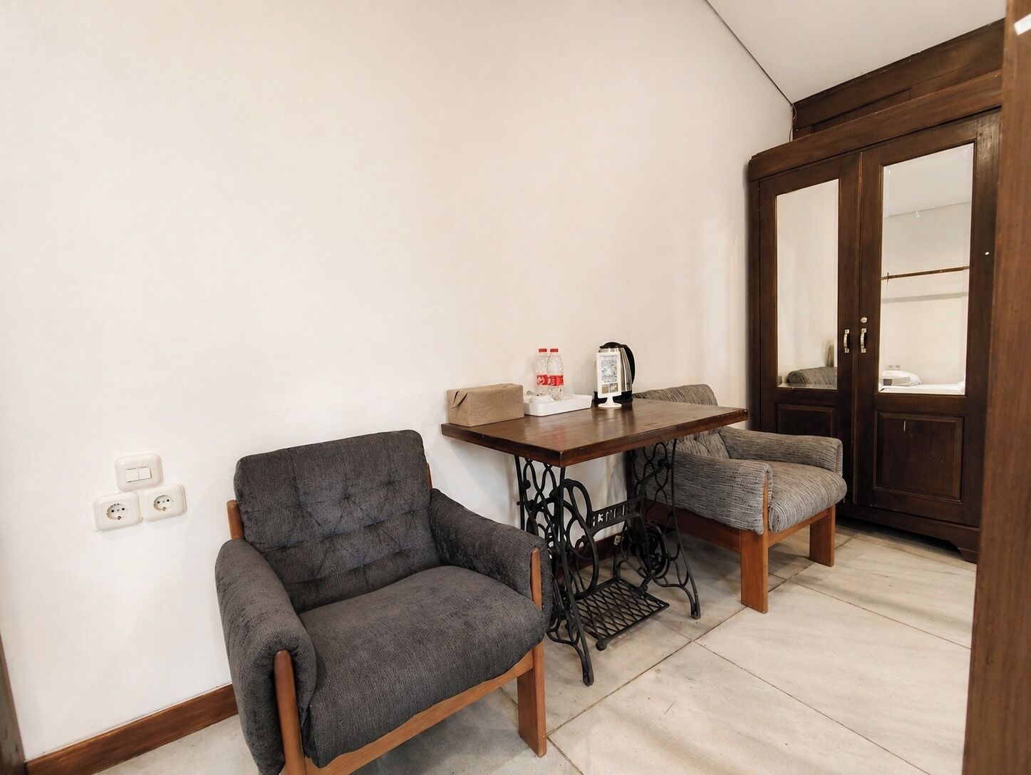 A room with a sofa, a small table with a kettle, and a cabinet.