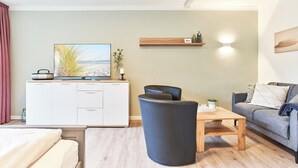 Ett modernt vardagsrum med en soffa, ett soffbord, en tv och ett skåp.
