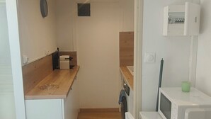 A compact kitchen with white cabinetry, a wooden countertop, and a microwave on a small white appliance. - Le Derroja - Perpignan (Perpignan)