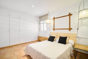 A bedroom with a bed, wooden headboard, bedside table, and wardrobe. - Villa in lámetlla de Mar (Sant Jordi d'Alfama)