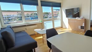 A modern room with a large window, a flat-screen TV, a table, and a sofa.