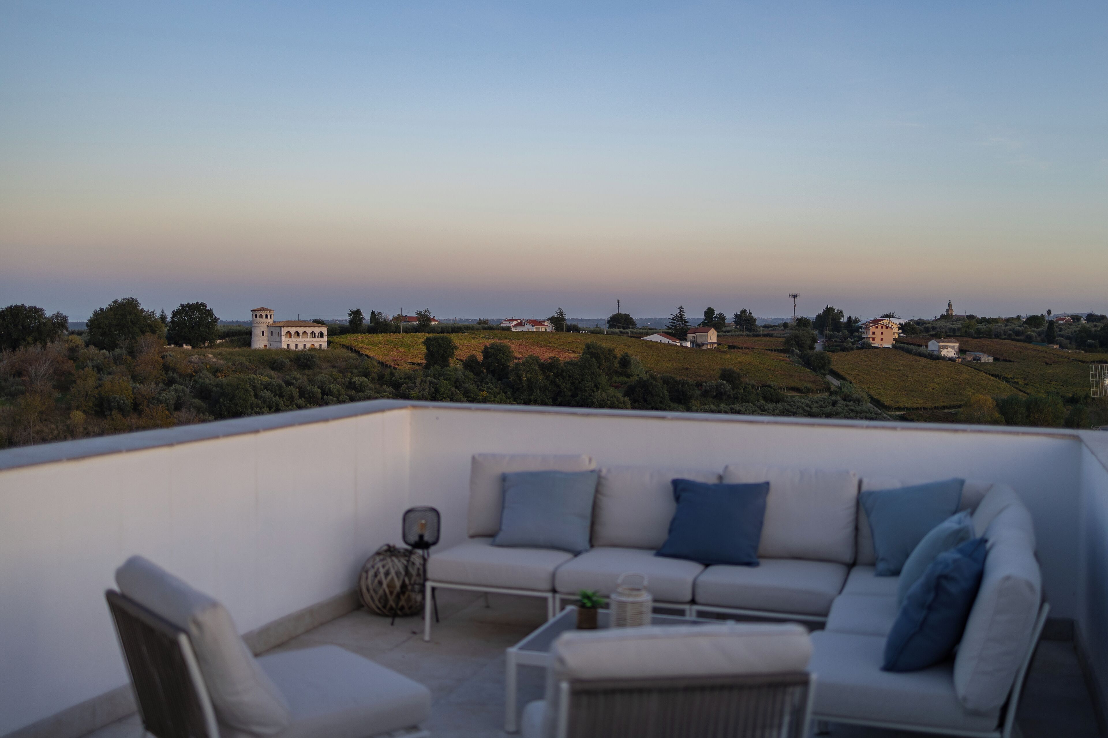 Terraza en la azotea con un sofá, sillas y una mesita.
