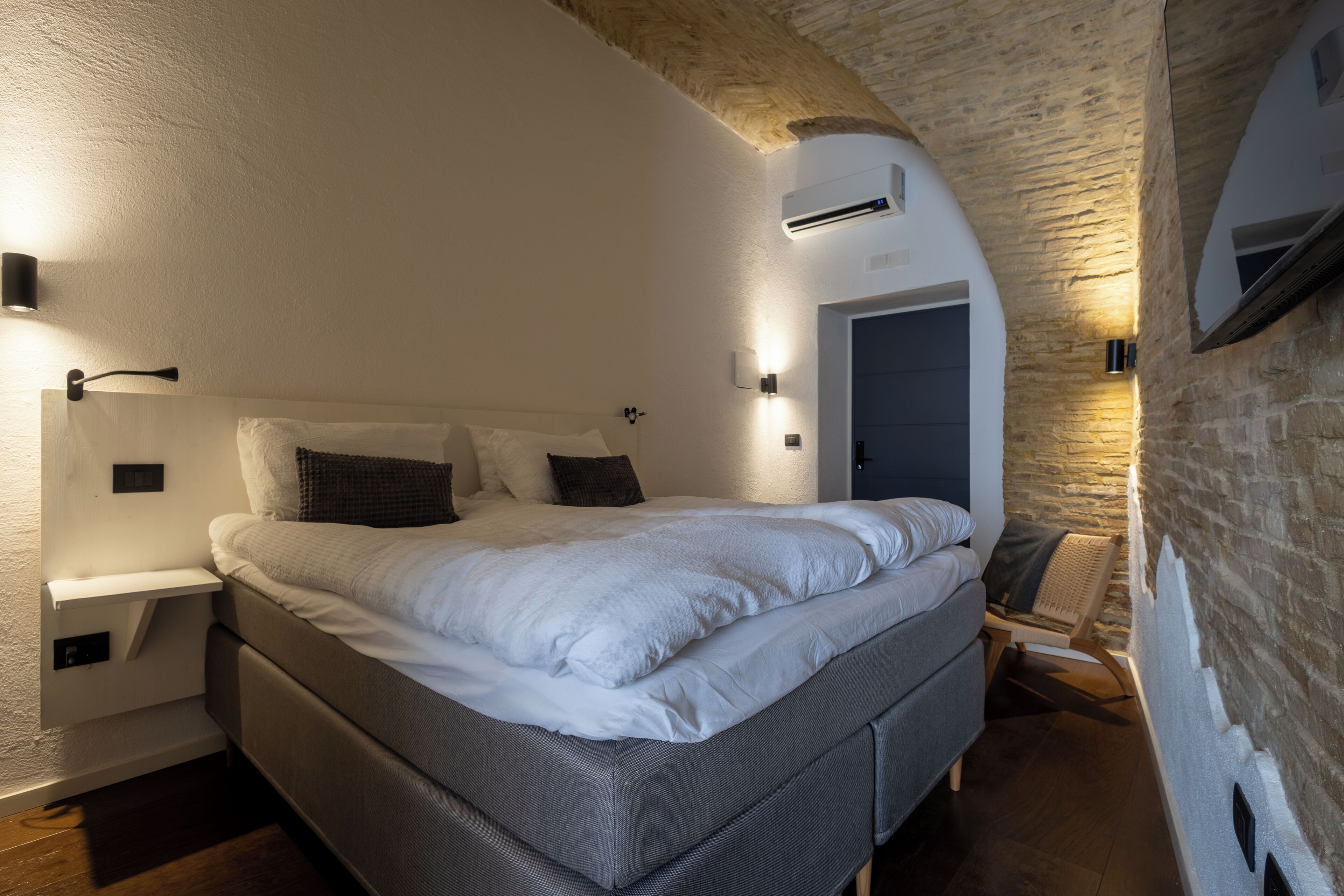 A bedroom with a bed, nightstands, and a reading chair.
