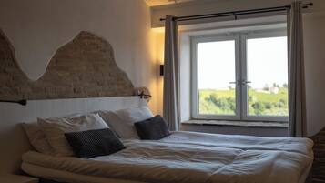 Ein Schlafzimmer mit einem großen Bett, einem Ziegelstein-Kopfstück und einem Fenster mit Vorhängen.
