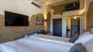 Een slaapkamer met een groot bed, een flatscreen televisie aan de muur, een verwarming en een deur naar een badkamer.