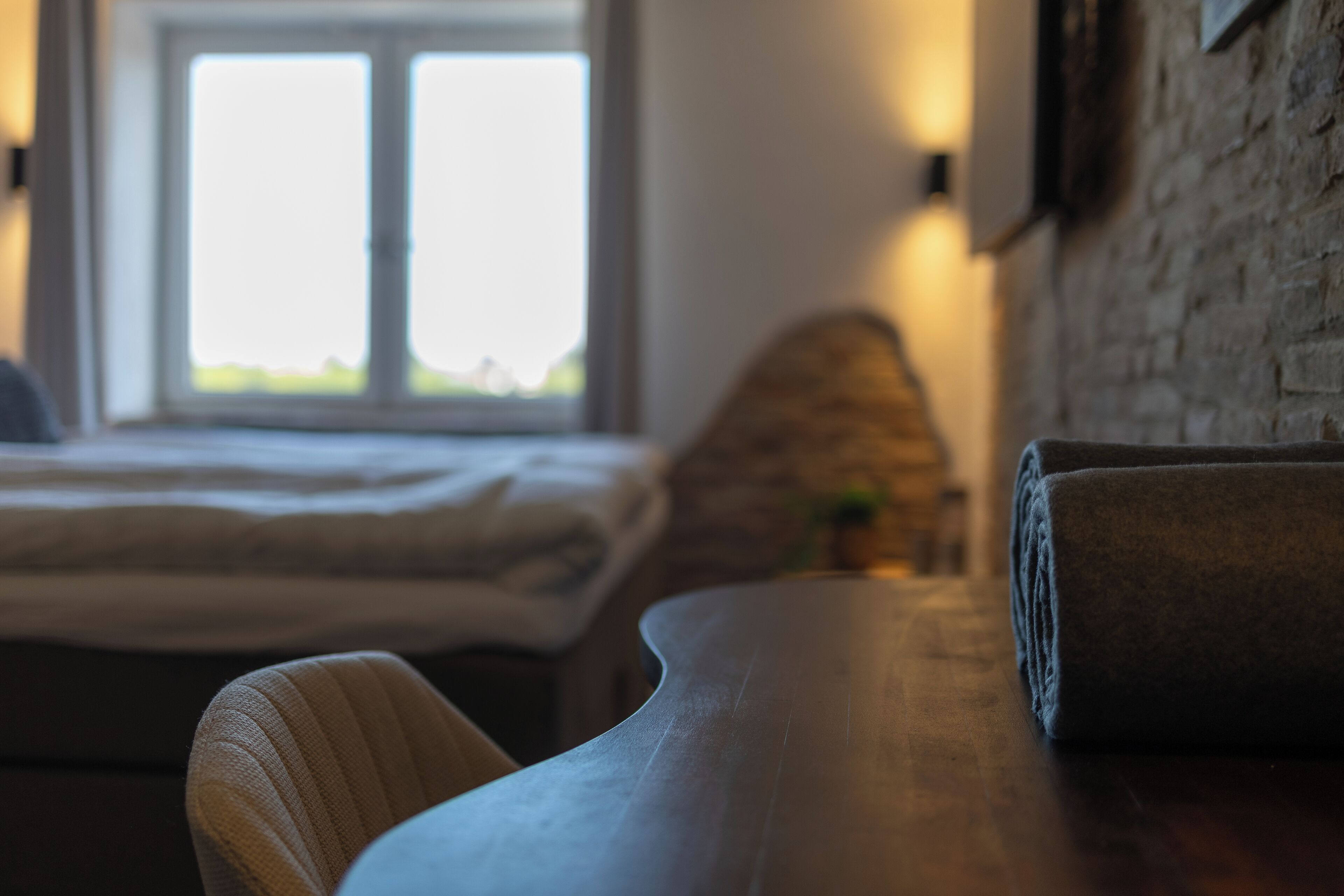 Um quarto com uma cama, uma mesa de madeira e uma janela.