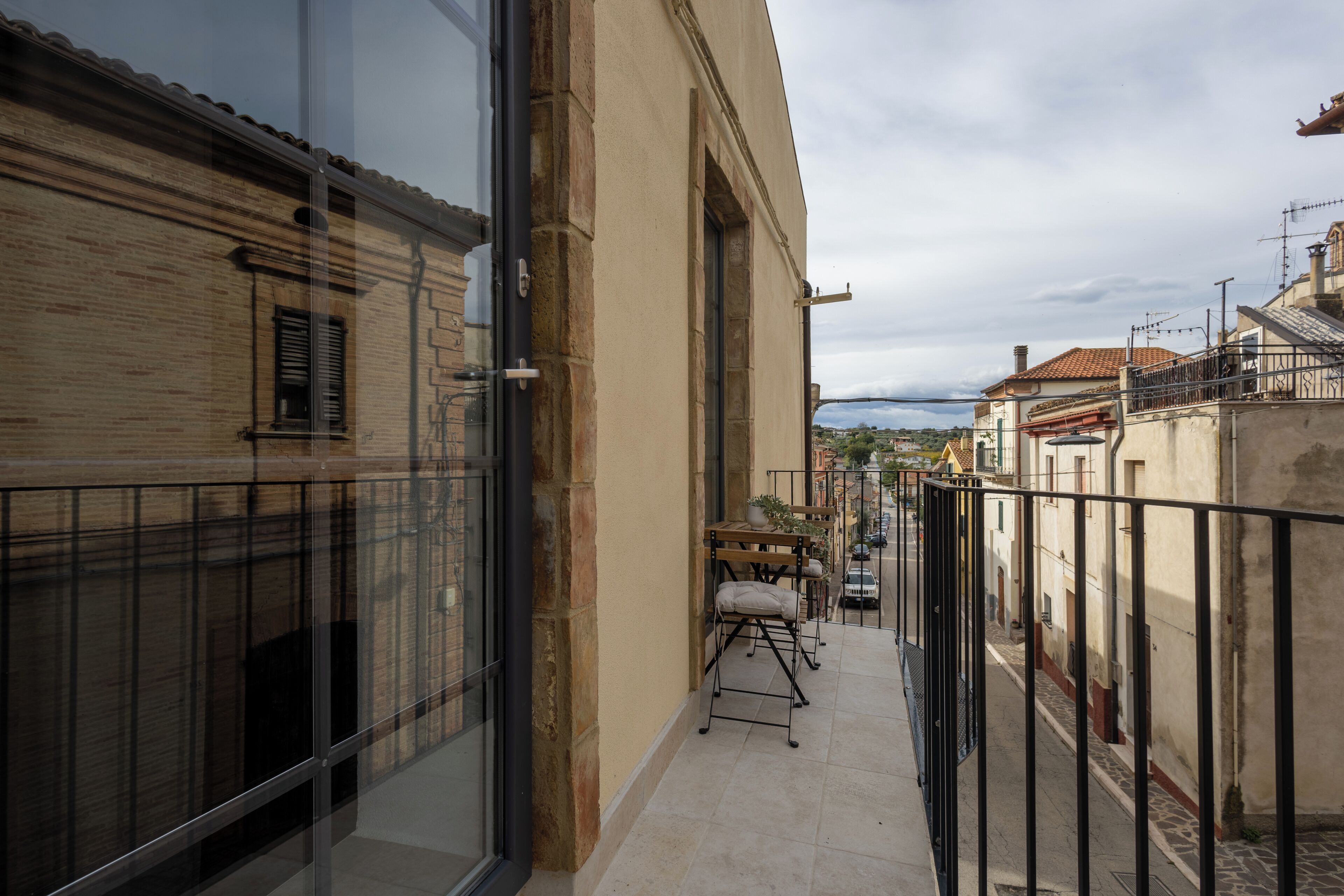 A narrow balcony with a view of a street and buildings.