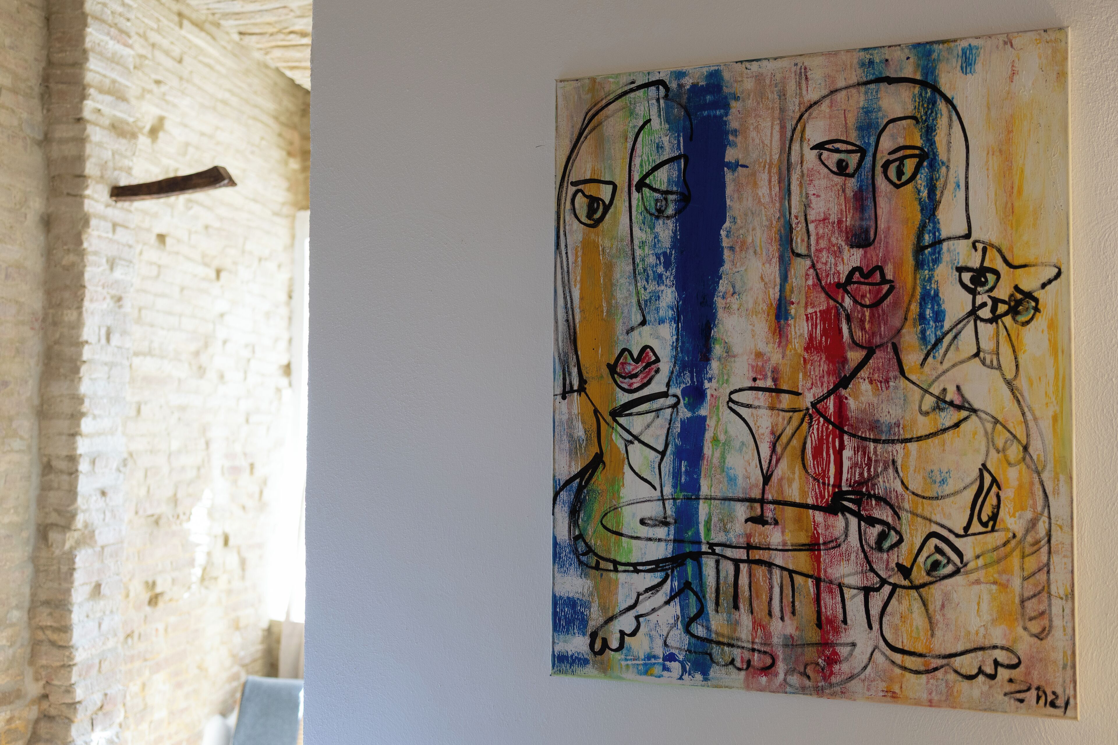 Una stanza con una parete in mattoni e un quadro astratto dai colori vivaci.