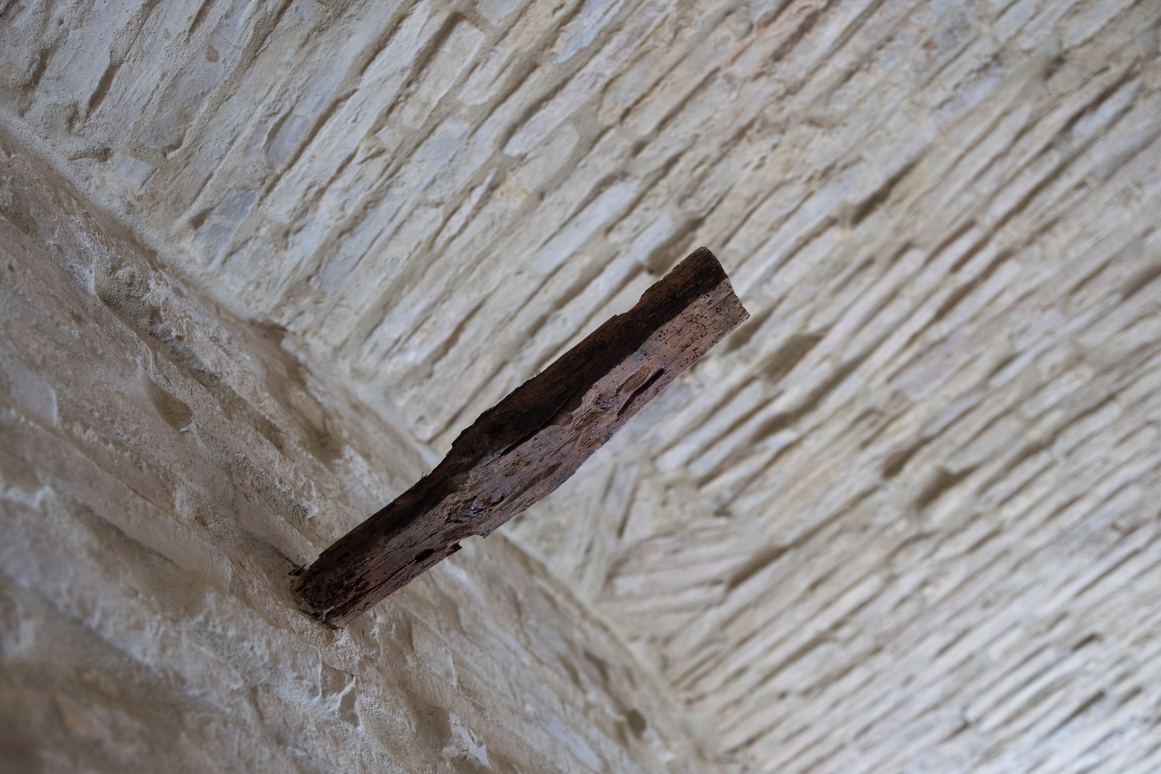 A textured wall with a wooden beam.